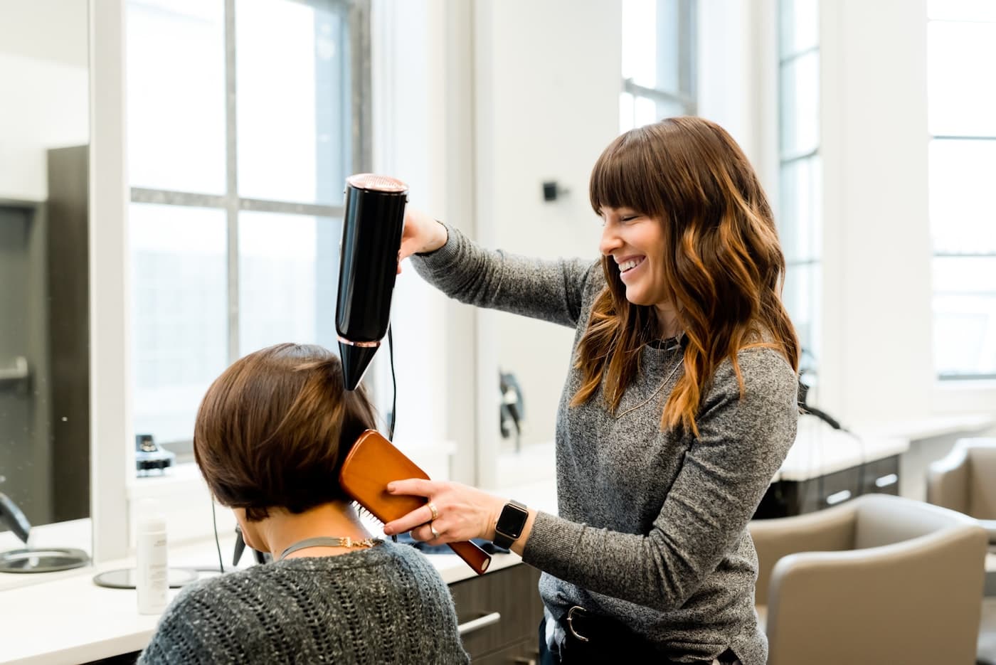 Profissional finalizando o cabelo de uma cliente no salão